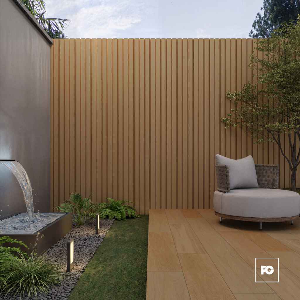 Modern backyard lounge with a tall tan wood slat privacy wall, a water feature fountain on the left, landscaping, and a round cushioned seating area on a wooden deck.